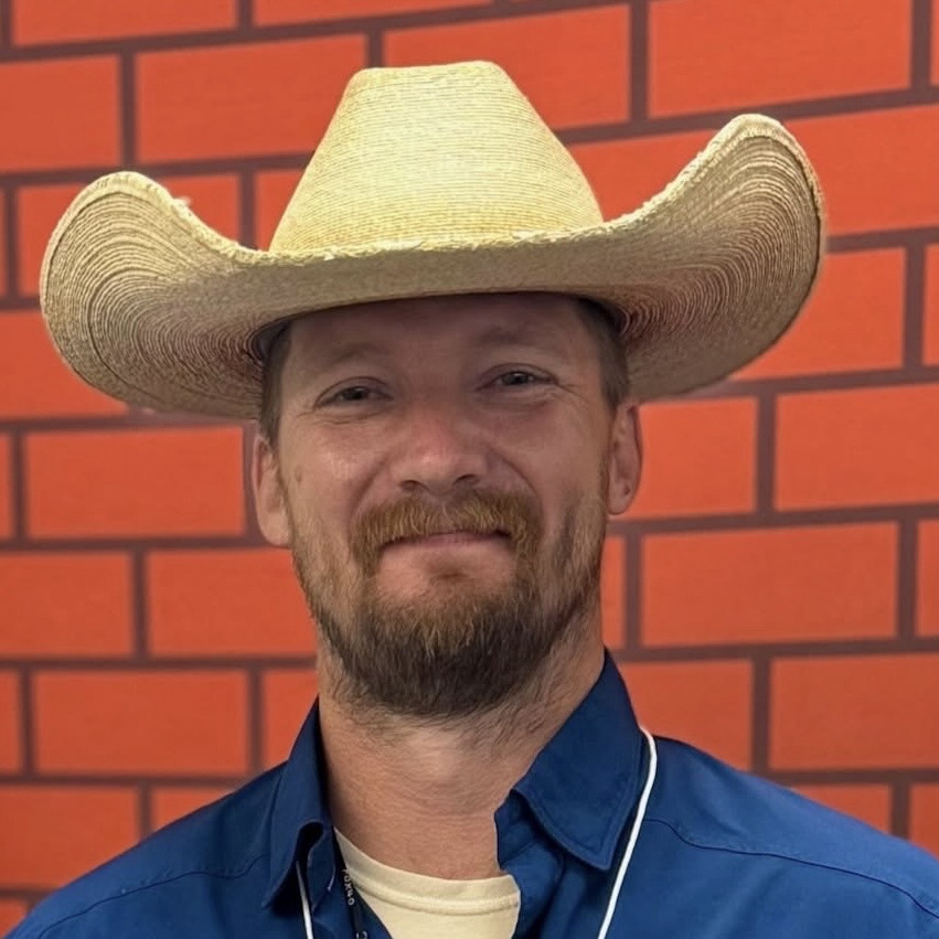 Russel Ramsey smiling in a cowboy hat
